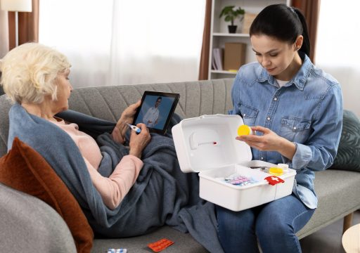 Worried woman examining pills while her elderly ill mother holding tablet and explaining her symptoms to doctor at video call at home. Take care of parents concept. Stock photo