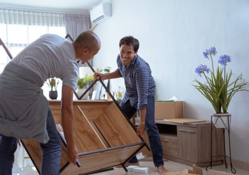 two male woodworker assembling new furniture at customer's house together